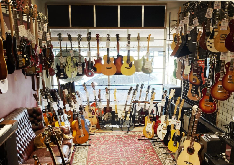 Inside the Westend Guitar Co. showroom: walls of vintage electric and acoustic guitars above a Persian rug and a leather chesterfield